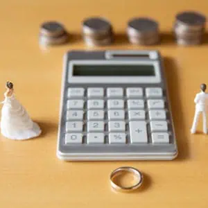 A calculator, wedding ring, and a bride and groom symbolize love, commitment, and the merging of two lives - Law Offices Of David Bliven